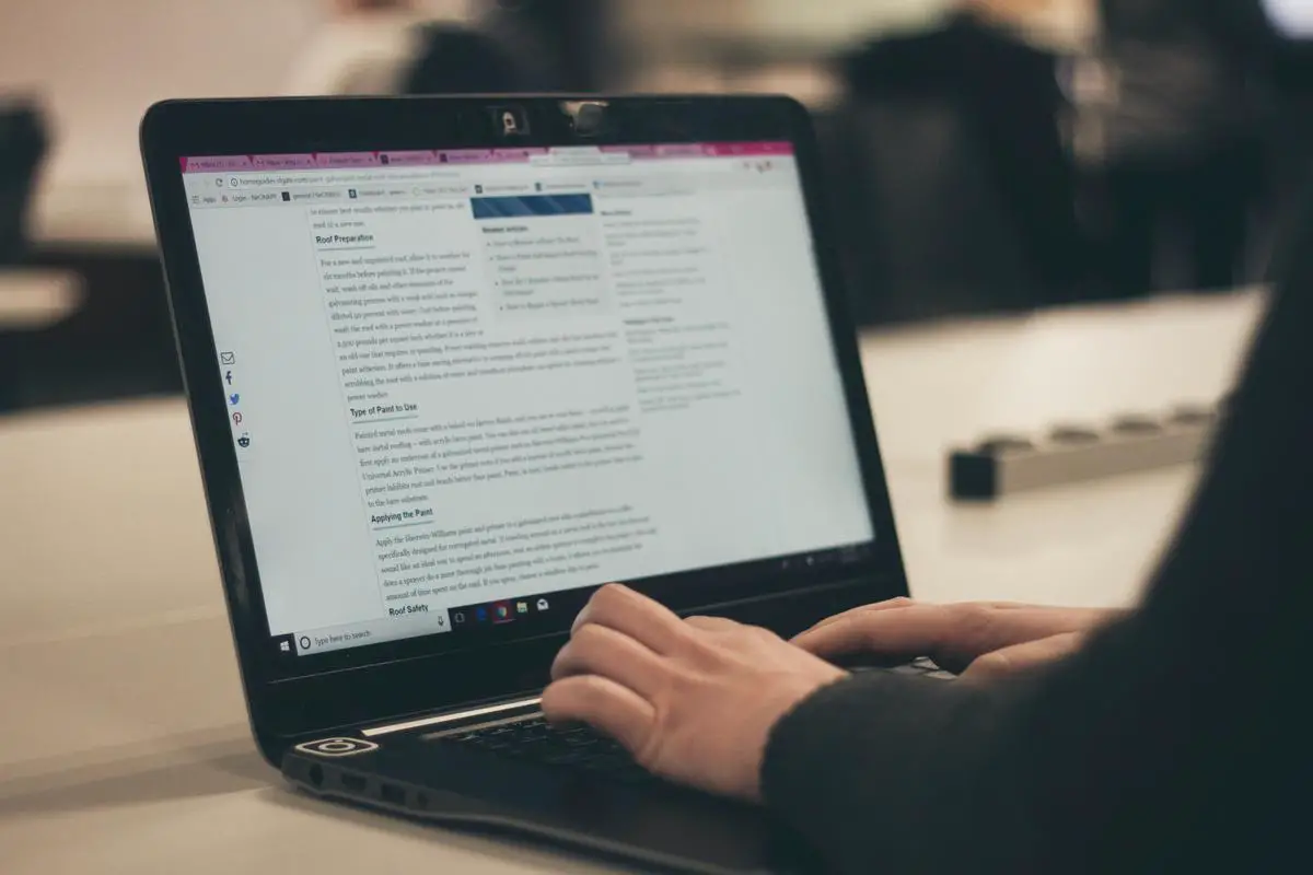 A blogger writing content on a laptop surrounded by research materials and SEO strategy notes