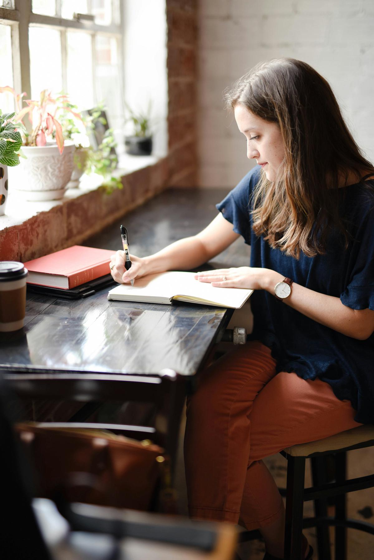 A person writing on a laptop with a cup of coffee and a notepad nearby, representing the creation of high-quality, engaging content for SEO.